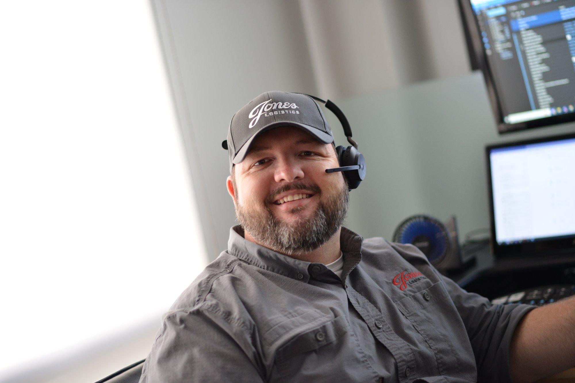 Jones Logistics (JoLo) Carrier Sales Representative on headset at computer smiling
