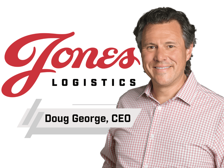 Doug George, new CEO for Jones Logistics, stands next to the Jones Logistics logo, smiling and wearing a red and white checkered shirt.