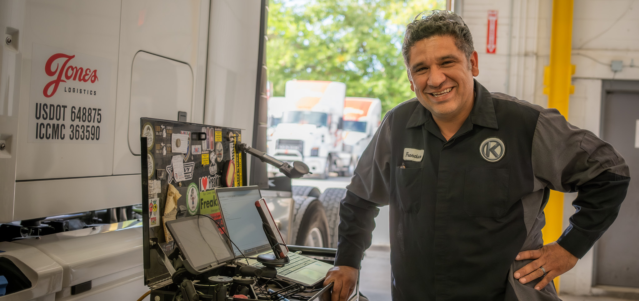 Francisco Nunez stands smiling with his hand on his waist next to a Jones Logistics Dedicated truck.